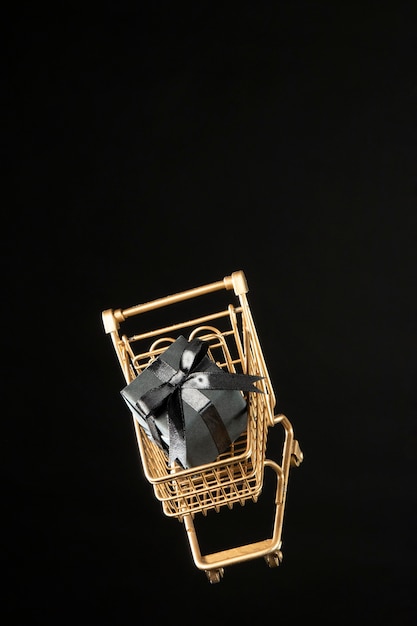 Free photo golden shopping cart with black gift