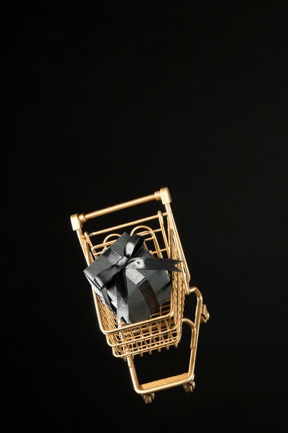 Golden shopping cart with black gift