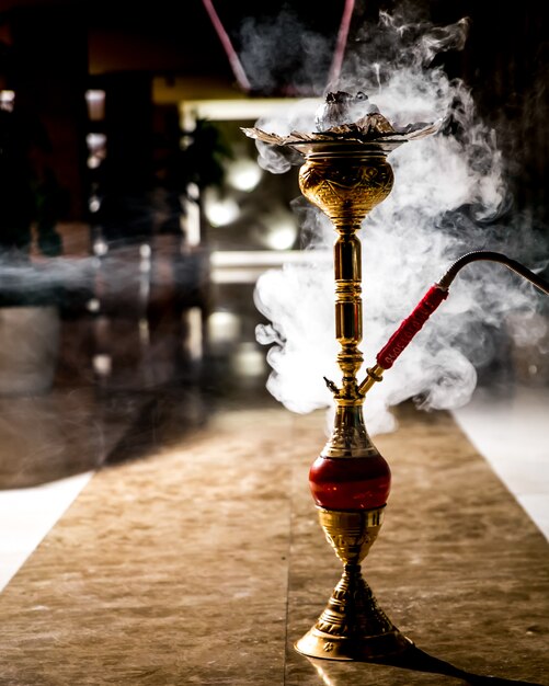 Golden steaming hookah on the floor side view