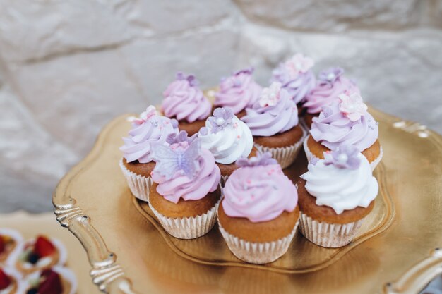 Golden tray with cupcakes covered with dim pink cream