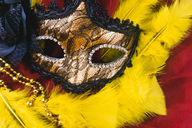 Golden venetian mask on yellow feathers