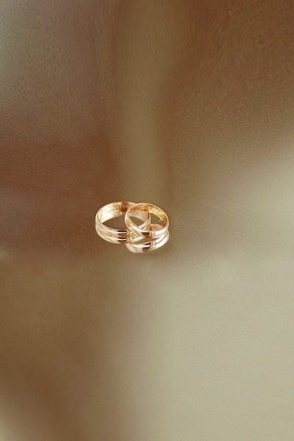 Golden wedding rings lie on transparent table