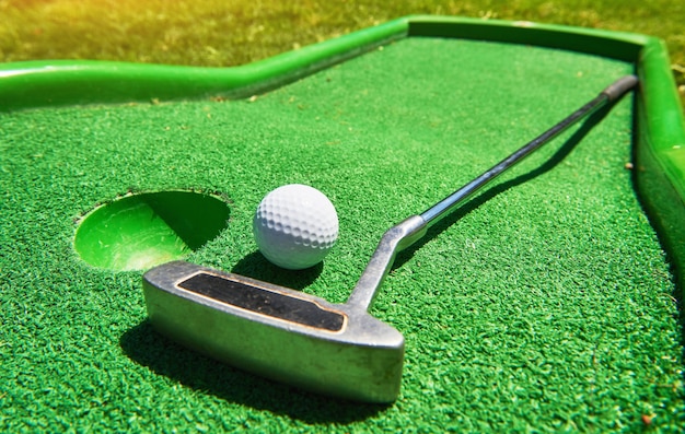 Мяч для гольфа и гольф-клуб на искусственной траве.