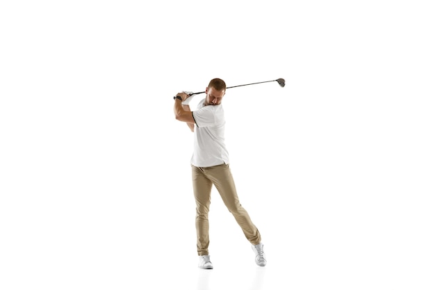 コピースペースで白い壁に分離されたスイングを取っている白いシャツを着たゴルフプレーヤー。明るい感情と表情で練習するプロ選手。スポーツコンセプト。