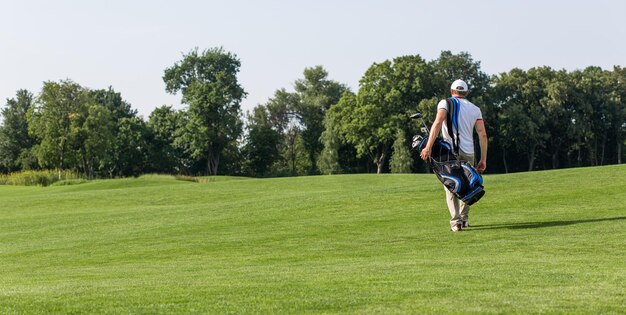 Игрок в гольф с сумкой для гольфа идет по полю