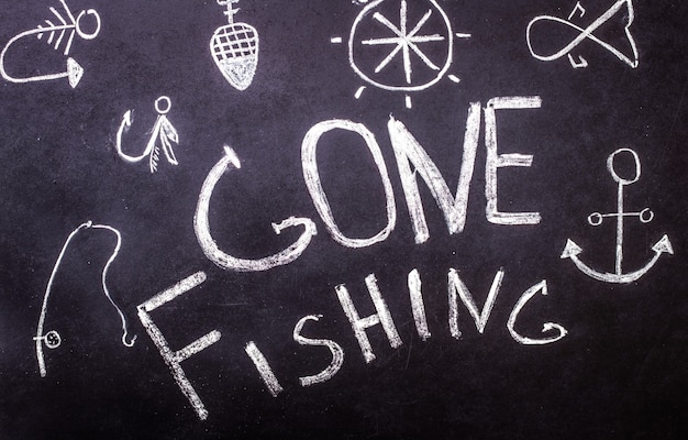 Free photo gone fishing chalk inscription on chalkboard with marine drawings