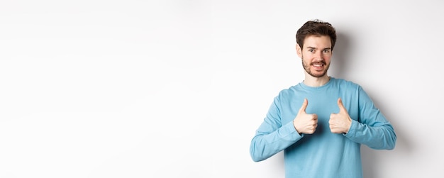 Foto gratuita buona scelta uomo caucasico attraente con la barba che mostra i pollici in su e sorride come e approva bene