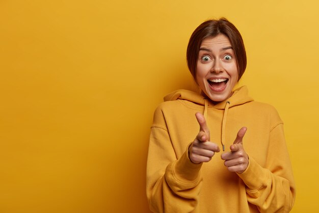 good choice. happy optimistic young woman makes finger pistols gesture, congratulates you and gives blessing, has overjoyed face expression