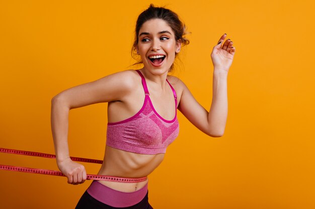 Good-humoured fitness woman using measure tape