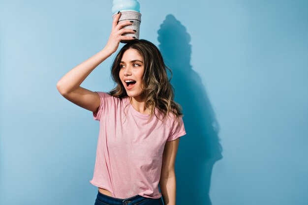 Good-humoured lady with wavy hairstyle fooling around in studio