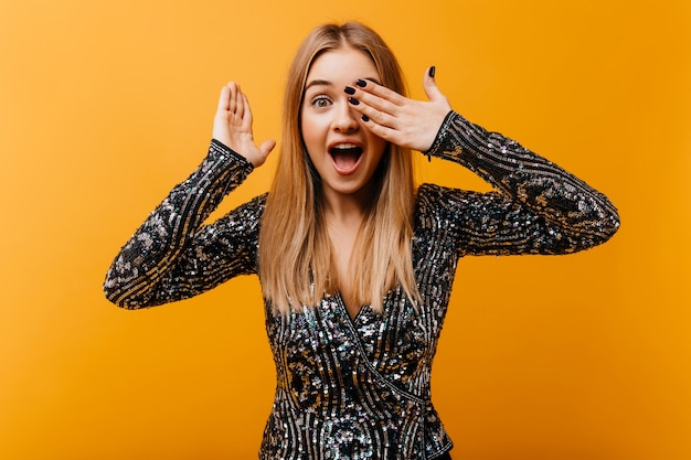 Good-humoured white woman having fun on orange. Indoor portrait of jocund blinde woman making funny faces.