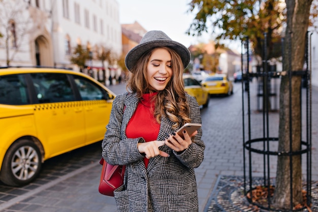 Free photo good-looking business woman texting message while walking on the street