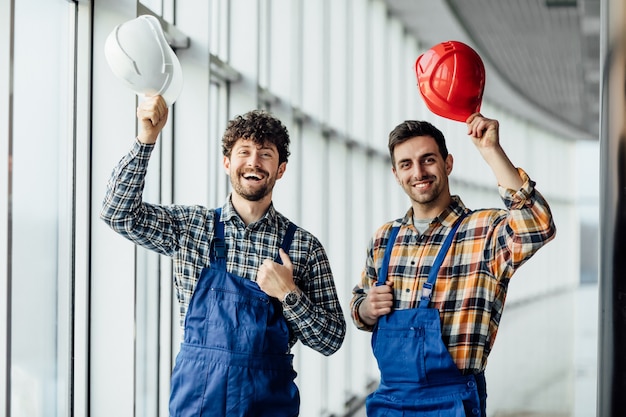 Free photo good looking construction worker sharing with the experience with a colleague, holding helmet