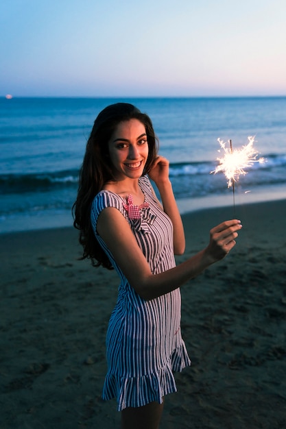 Foto gratuita ragazza carina con sparkler in spiaggia