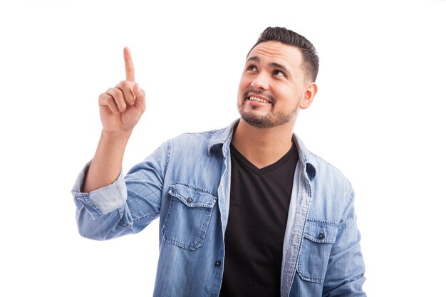 Good looking guy dressed casually pointing and looking up towards copy space