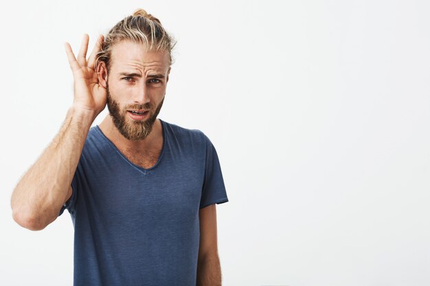 Good-looking swedish guy with beard and cool hairstyle holding hand near ear