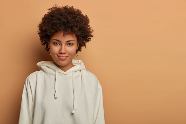 Good looking woman has Afro hair, has direct gaze and tender smile