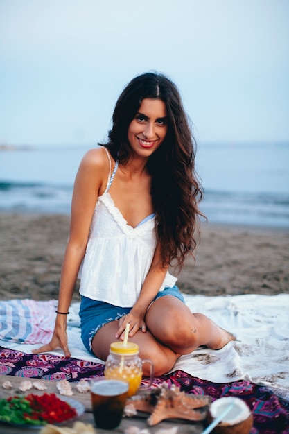 Бесплатное фото Хорошенькая женщина, сидящая на пляже