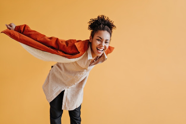 Good-looking woman in windbreaker fooling around on yellow wall