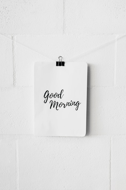 Free photo good morning text on paper attach with bulldog paper clip over the white wall