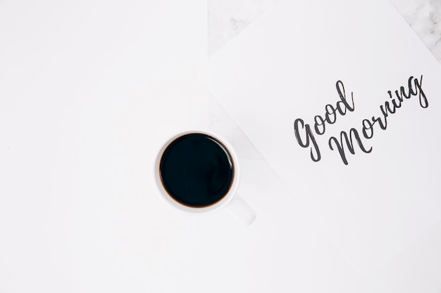 Good morning text on paper with coffee cup against white background