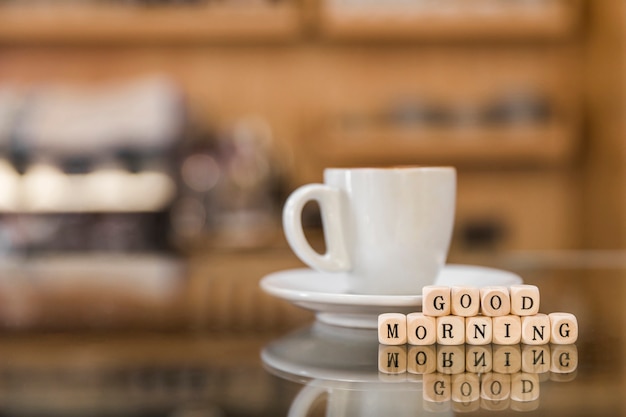 Buongiorno blocchi di legno con una tazza di caffè sul bancone di vetro