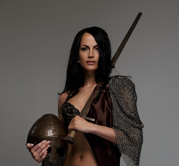 Бесплатное фото Великолепная воительница позирует с мечом и шлемом
