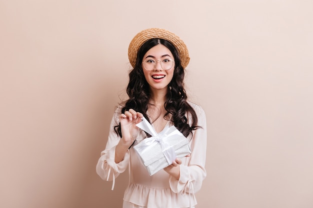 Gorgeous asian woman opening birthday present. Front view of glad korean woman with gift.