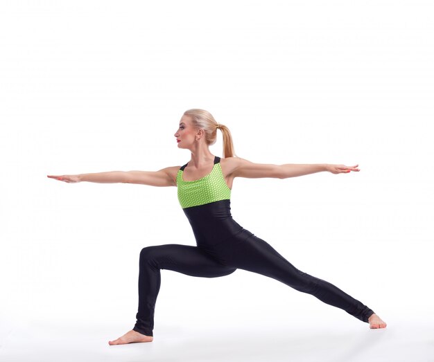 gorgeous blonde haired fit woman performing yoga warrior asana