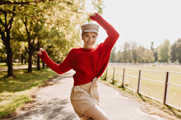Великолепная блондинка в модной сезонной одежде веселится в парке. Красивая молодая женщина, чувствуя себя счастливой на открытом воздухе.
