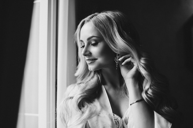 Gorgeous bride standing near balcony and looking in big window.