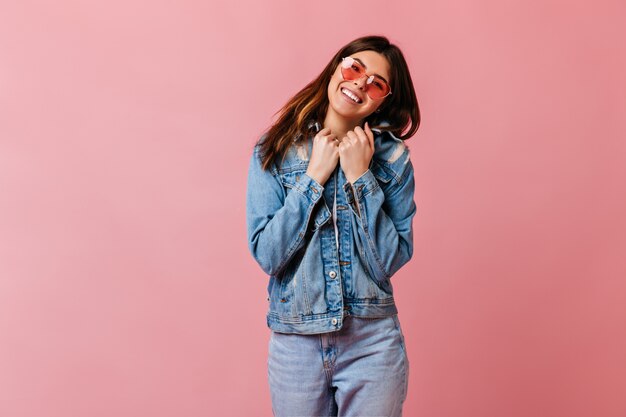 긍정적 인 감정을 표현하는 데님 재킷에 화려한 소녀. 분홍색 배경에 고립 유행 백인 여자의 스튜디오 샷.