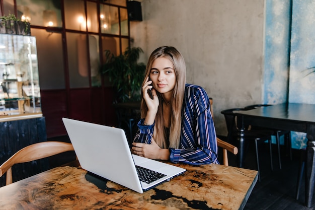 Splendida ragazza seduta al caffè con il suo laptop e guardandosi intorno. tiro al coperto di splendida signora bianca in posa con il computer.