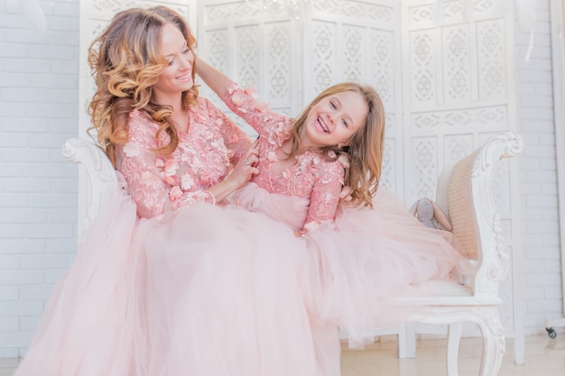 Gorgeous mom and daughter dressed like princesses in the same clothes pose