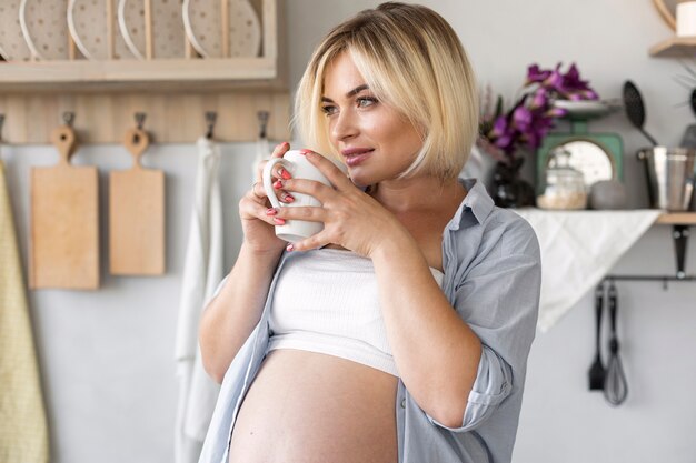 お茶のカップを保持している豪華な妊娠中の女性