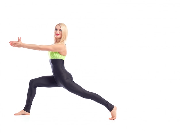 gorgeous red lipped female in sportswear doing warrior yoga asana