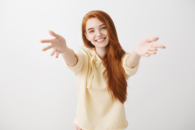 Gorgeous smiling redhead girl reaching hands forward to hold something