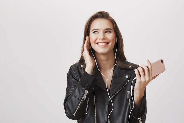 Великолепная улыбающаяся женщина в наушниках слушает музыку