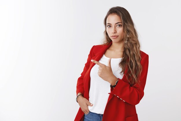옆으로 손가락을 가리키는 빨간색 트렌디한 재킷을 입은 멋지고 성공적인 현대 여성 사업가