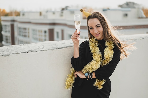 Donna splendida in vestito nero che tiene un bicchiere di champagne