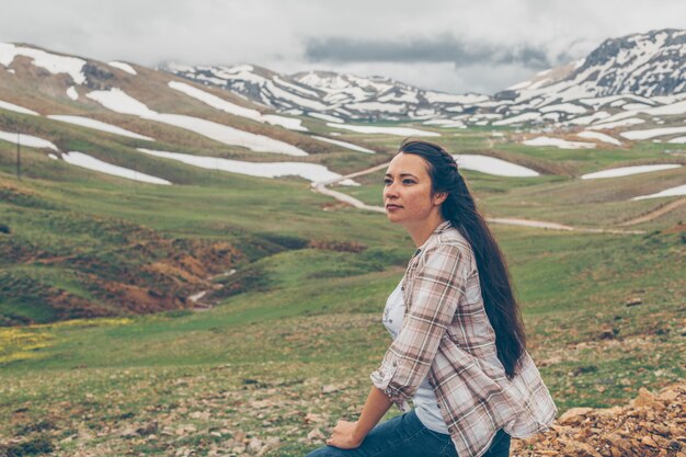 Gorgeous woman looking at hills during daytime and looking thoughtful