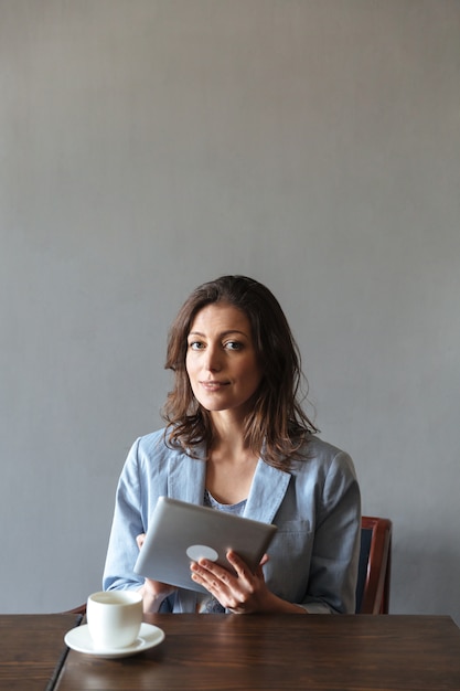 Free photo gorgeous woman sitting indoors using tablet computer.