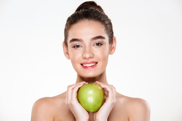 gorgeous woman with brown hair in bun holding big green apple in both hands like heart shape