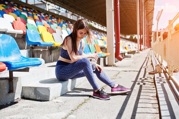 スタジアムの椅子に座っているゴージャスな若いフィットの女性