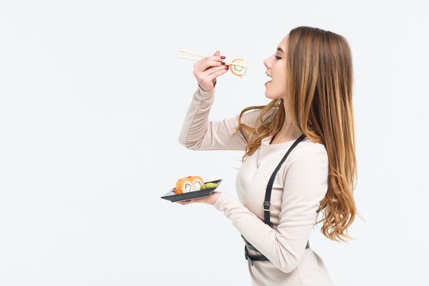 Gorgeous, young woman put piece of roll into mouth