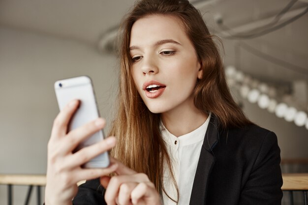 Gorgeous young woman using mobile phone at co-working space