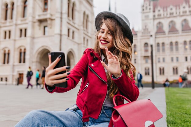 Gorgeous young woman waving hand on city wall during video call