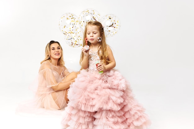 Gorgeous young woman wearing low neck strapless dress celebrating birthday with her daughter