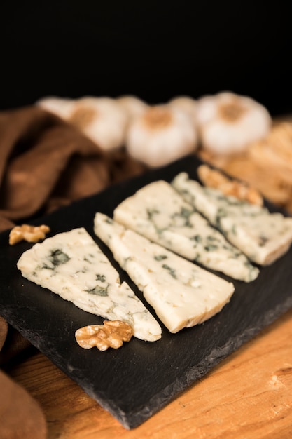 Free photo gorgonzola cheese slices and walnut on black stone