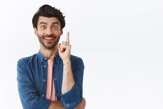 Got excellent idea Creative goodlooking caucasian bearded man raise one finger and smiling astonished as have something say give good suggestion during meeting with coworkers white background